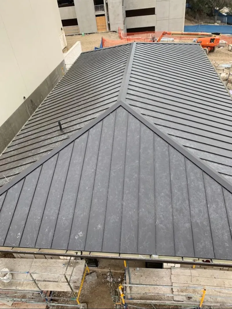 Commercial metal roof construction with crane equipment in Cinco Ranch